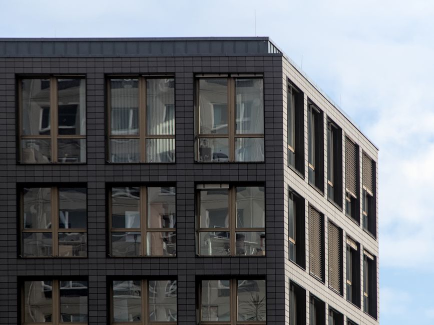 Corner view of a modern office building in Berlin with glass windows and a clear sky
