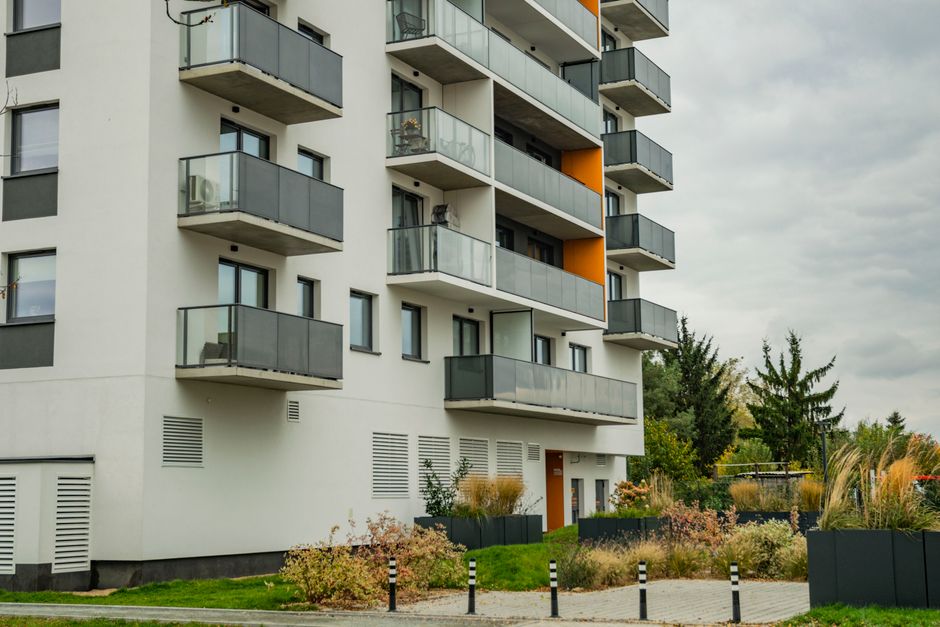 Contemporary apartment complex featuring glass balconies and landscaped surroundings